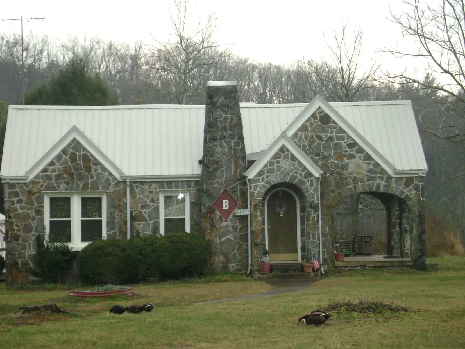 White metal roof on a stone cottage with steep gables in Norman