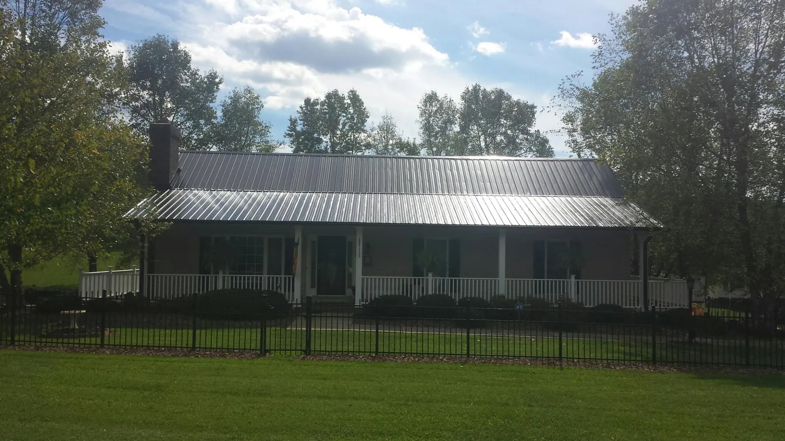 Gray metal roof on a brick ranch with a full width front porch — Gutter Guard Installation work by our crew in Norman