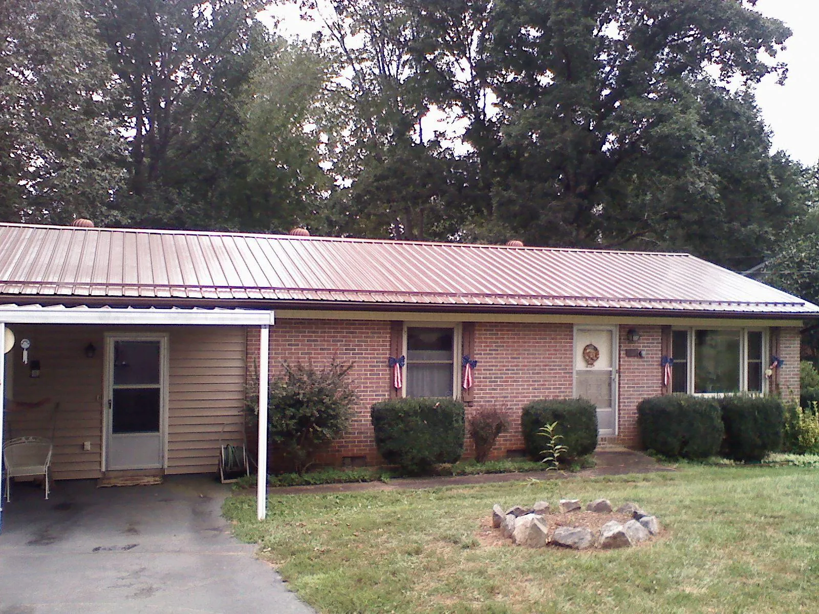 Bronze metal roof and carport on a brick ranch home — Roof Repair work by our crew in Norman